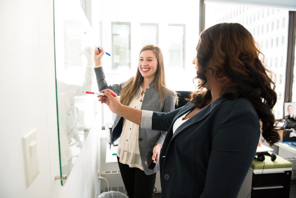 two-women-in-front-of-dry-erase-board-training-learning